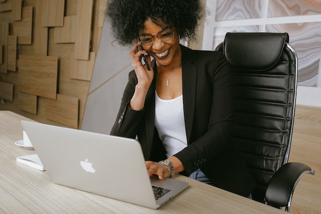 person smiling while on phone in front of laptop