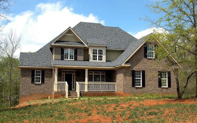 brick house in front of green and orange lawn with blue sky