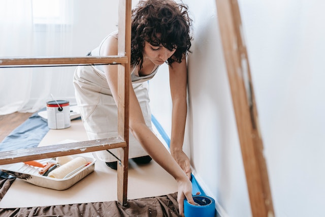 person painting a wall while crouched