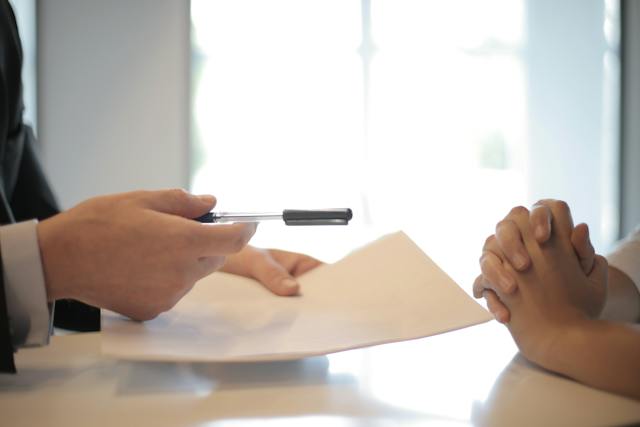 Someone handing a piece of paperwork to another person.