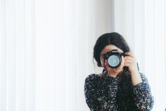 perso taking a picture in front of white curtains