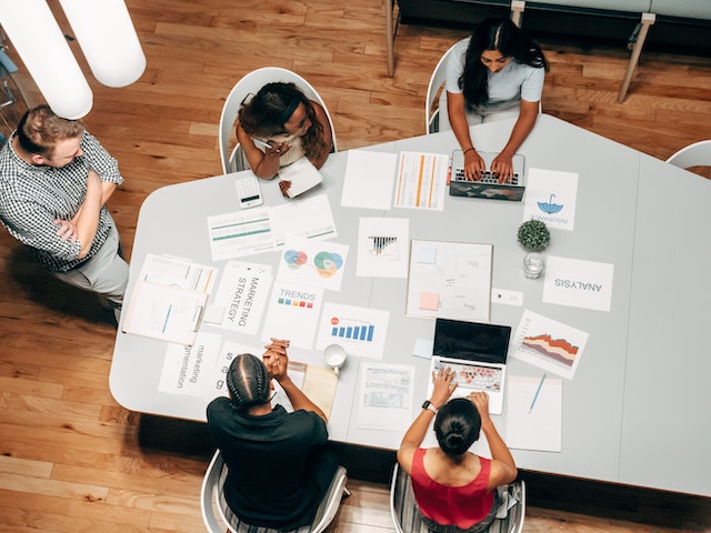 people sitting around a table covered in marketing materials