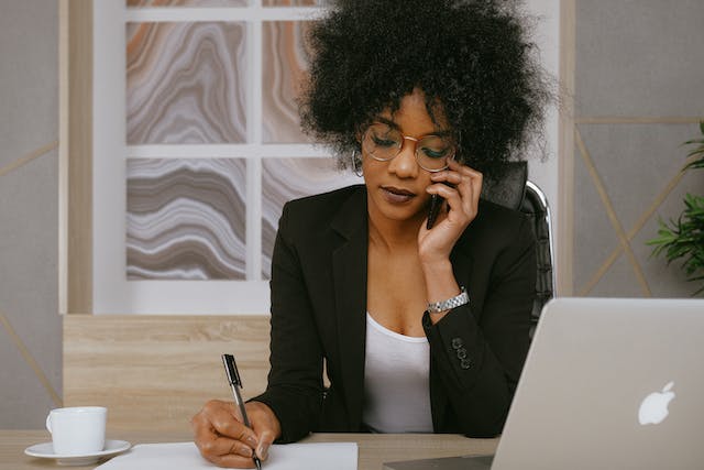 A person on a phone call and taking notes.